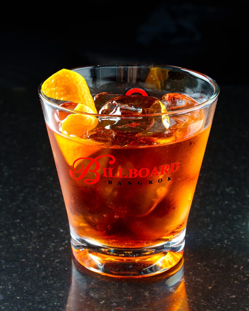 Cocktail menu photography of a Negroni over ice with an orange peel.