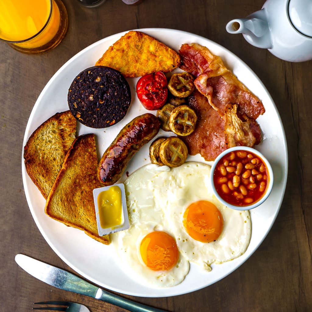 Full English breakfast with fried eggs, bacon, sausage, black pudding, baked beans, grilled tomatoes, mushrooms and toast.