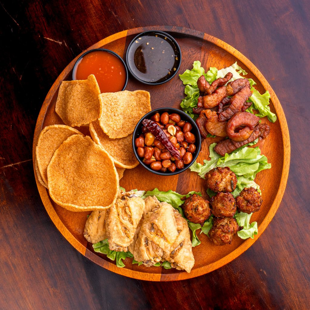 Thai snack platter with pork crackling, crispy pork, fried chicken, fish cakes, peanuts and dipping sauces.