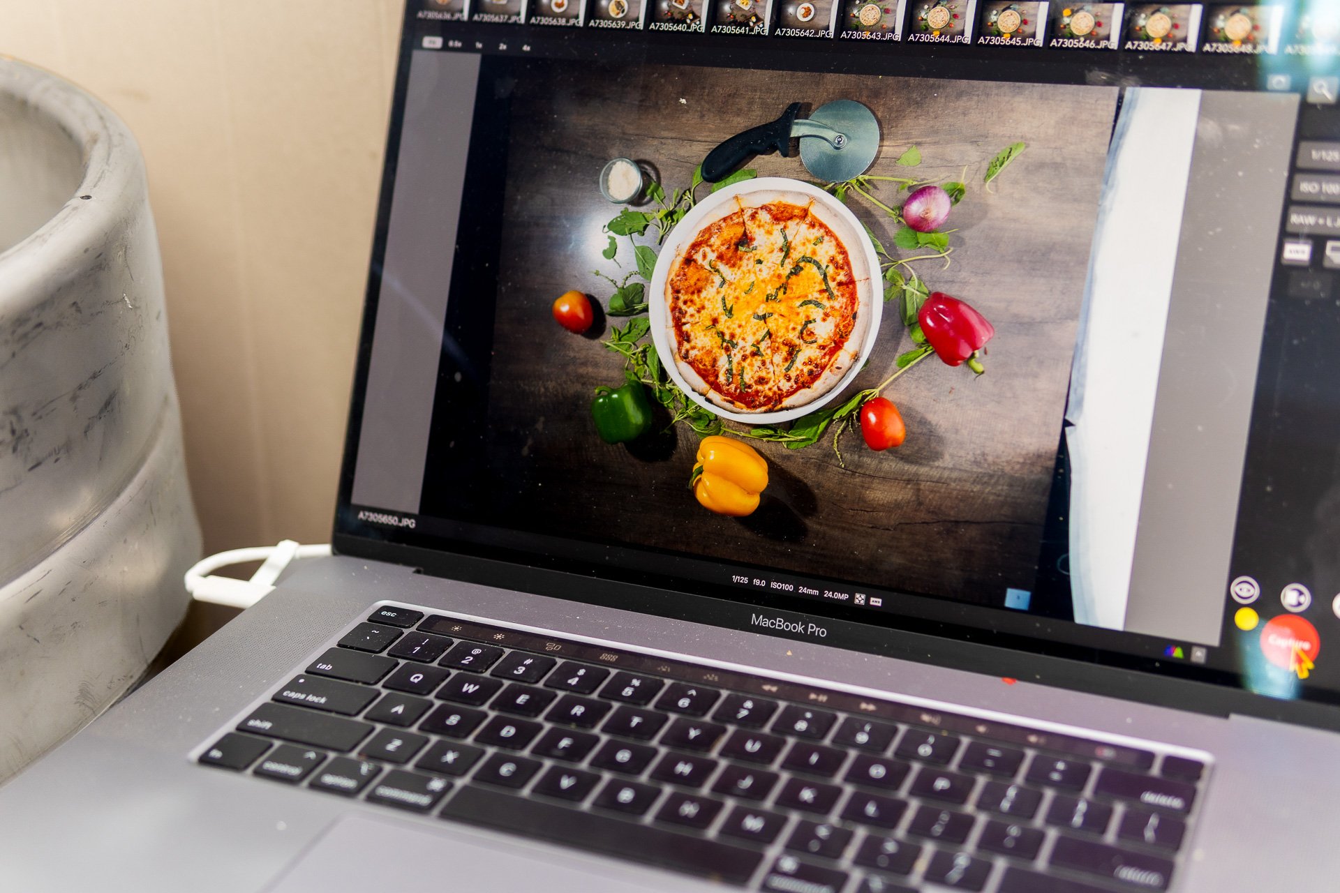 Laptop screen displaying an overhead food photograph of a cheese pizza.