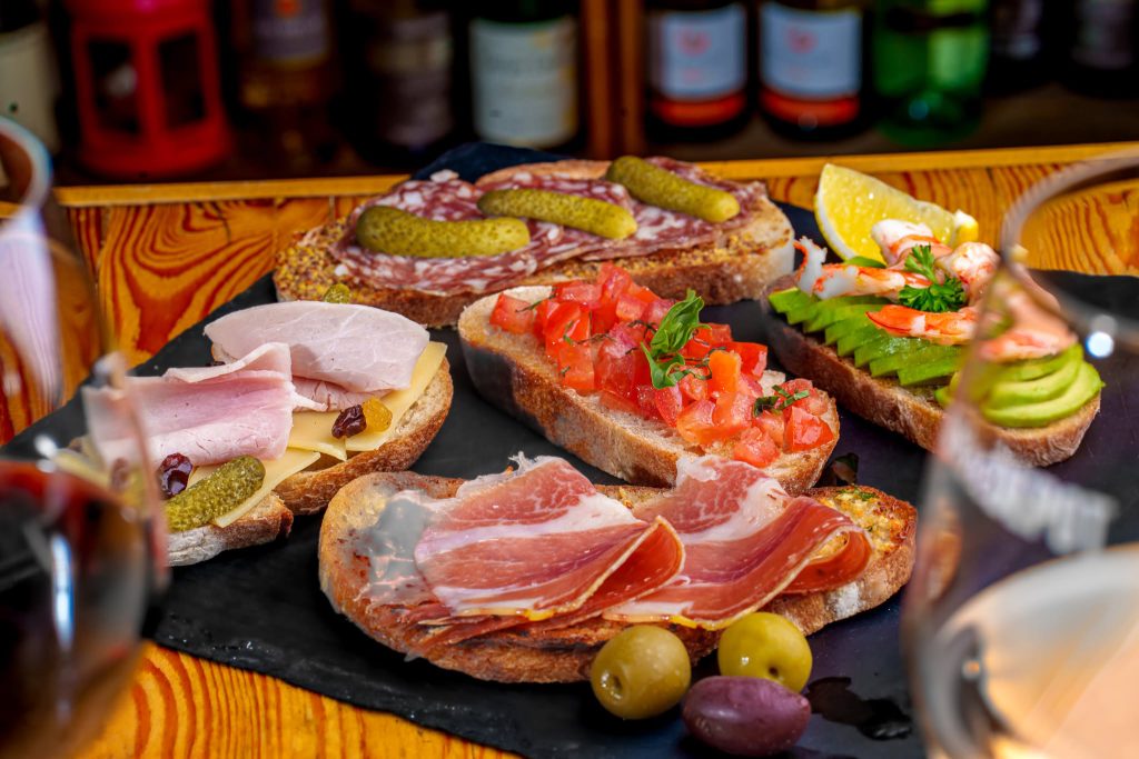Assorted open-faced tapas with cured meats, ham, cheese, tomato, avocado and prawns.